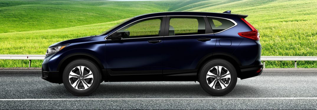 Purplish black 2019 Honda CR-V on a highway against a green field background, viewed from the side. It may or may not be bigger than past models.