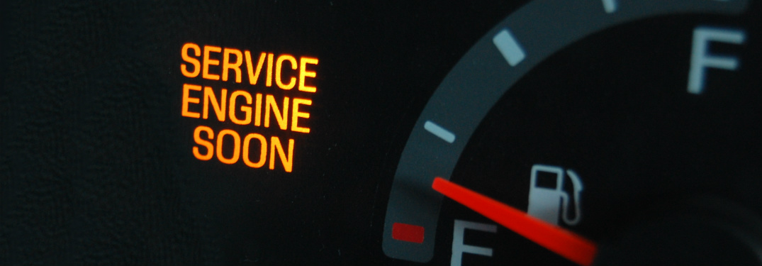 A check engine light on a dashboard is illuminated.
