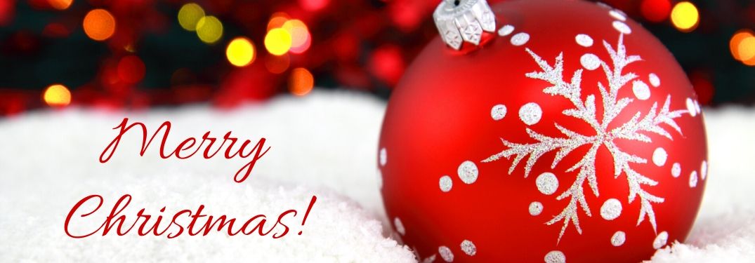 Close Up of Red Christmas Ornament in Snow with Red Merry Christmas Text