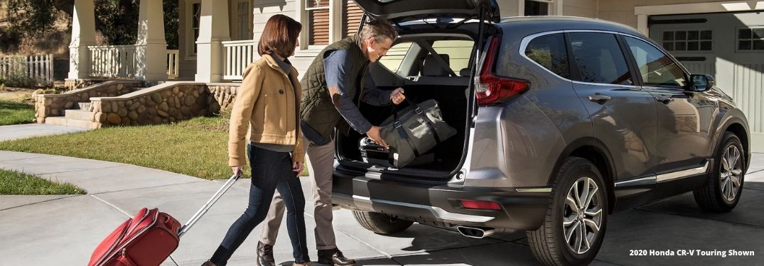 Man and Woman Loading Luggage in the Back of a 2020 Honda CR-V with White 2020 Honda CR-V Touring Shown Text in Lower Right