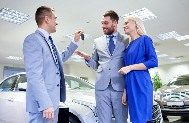 Salesman Handing a Couple Keys to a New Car