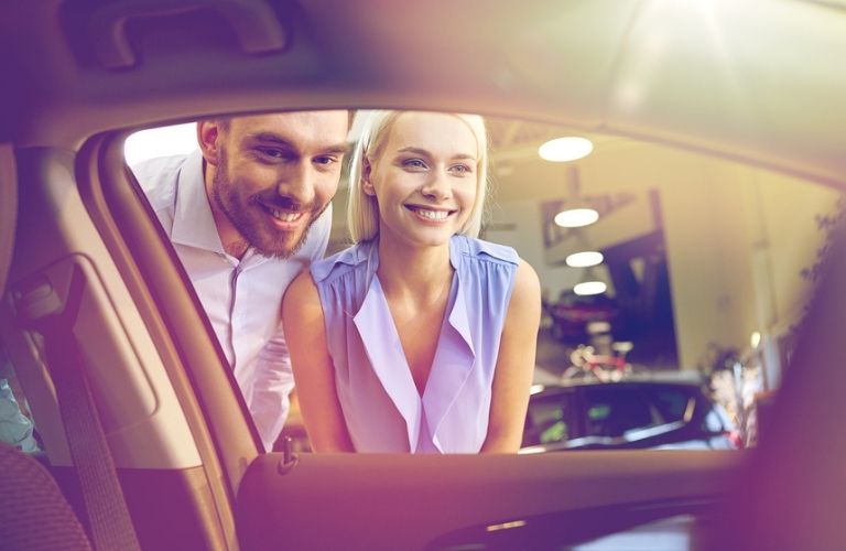 Man and Woman Looking in the Window of a New Car