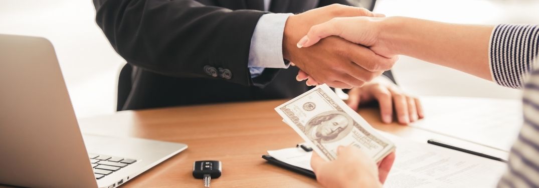 Car Salesman and Customer Shaking Hands at a Desk
