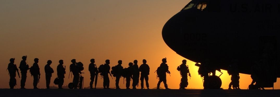 Silhouette of Soldiers Loading into an Airplane