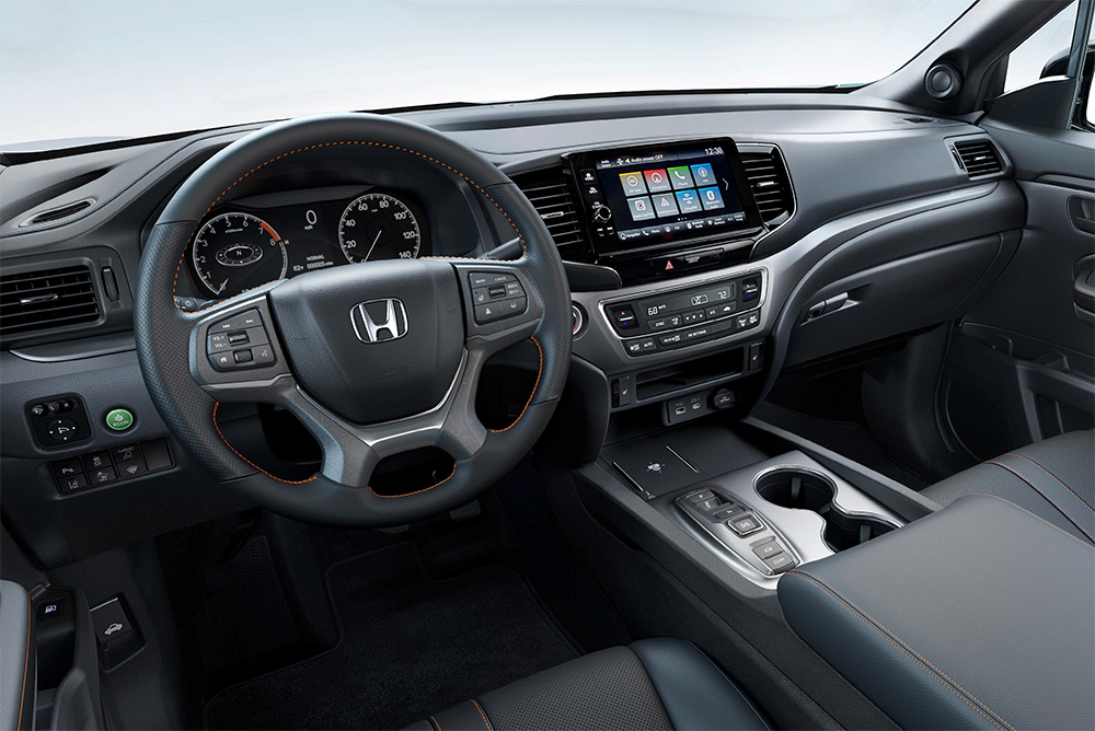 Interior shot of a modern vehicle dashboard, showing the steering wheel, digital instrument cluster, and a large central touchscreen display.