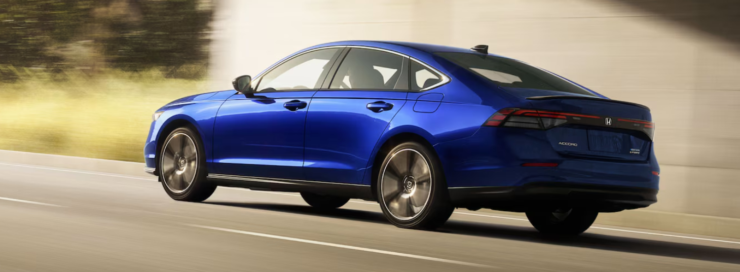 A blue Honda Accord sedan drives on a multi-lane highway, with the background blurred to convey speed.