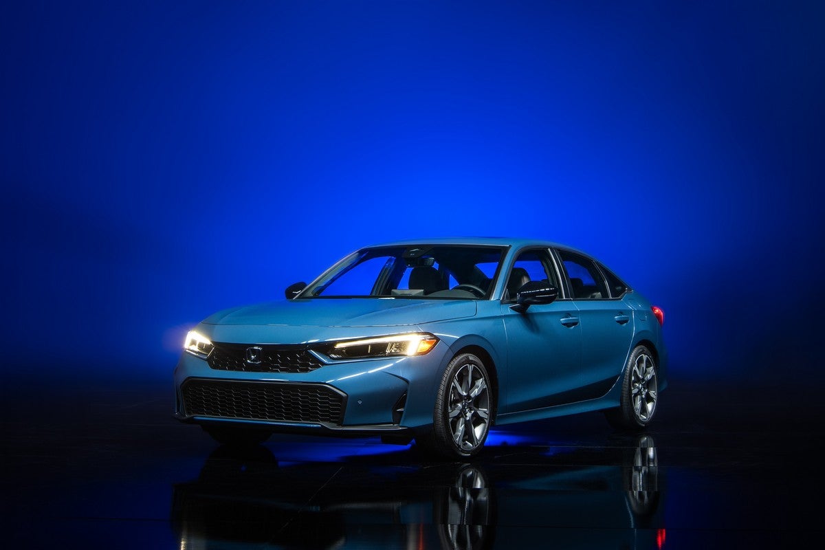 A blue 2026 Civic Hatchback in Phoenix is parked facing the viewer to the left in a dark showroom.