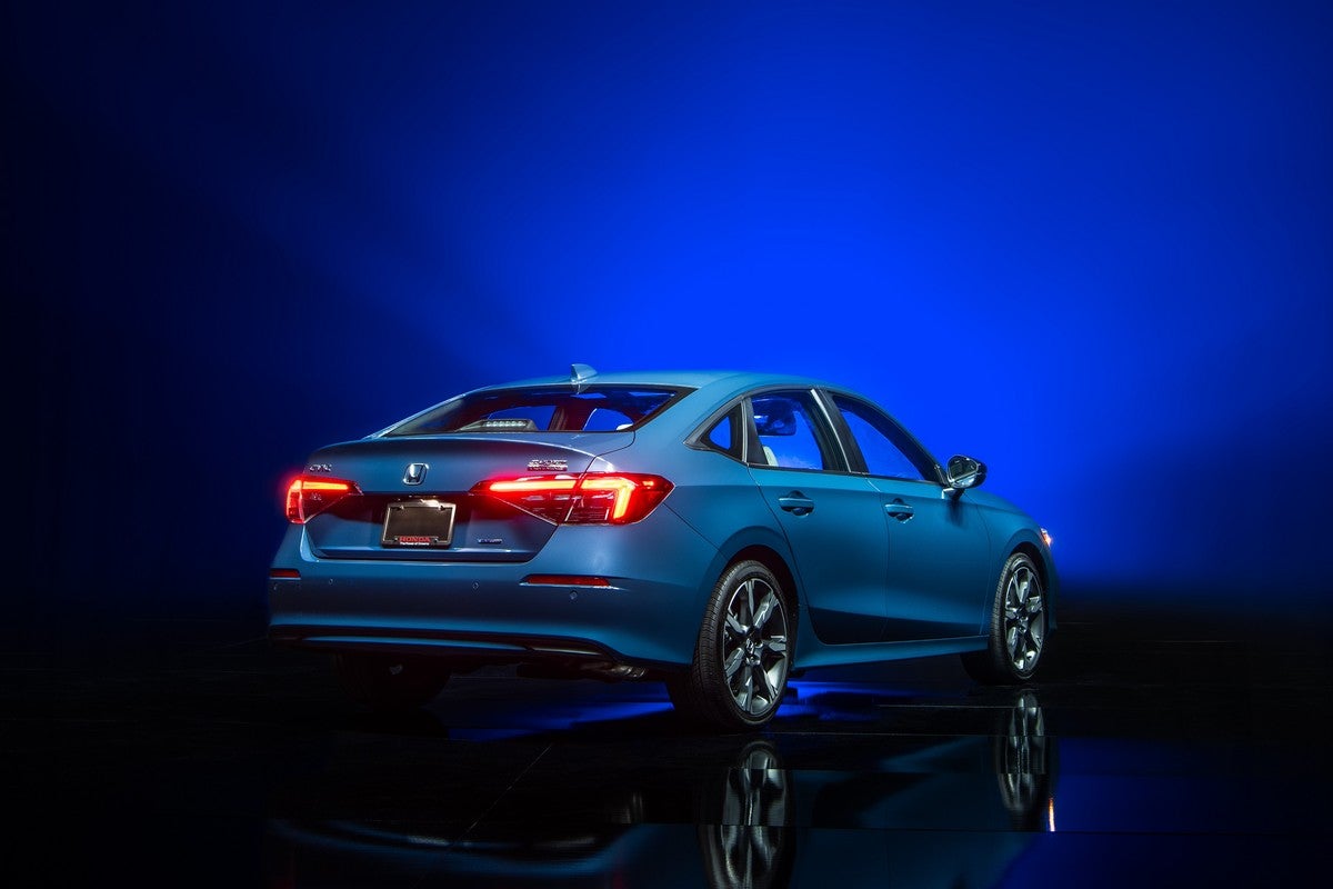 A blue new Civic Hatchback in Phoenix is parked facing away from the viewer to the right in a dark showroom.