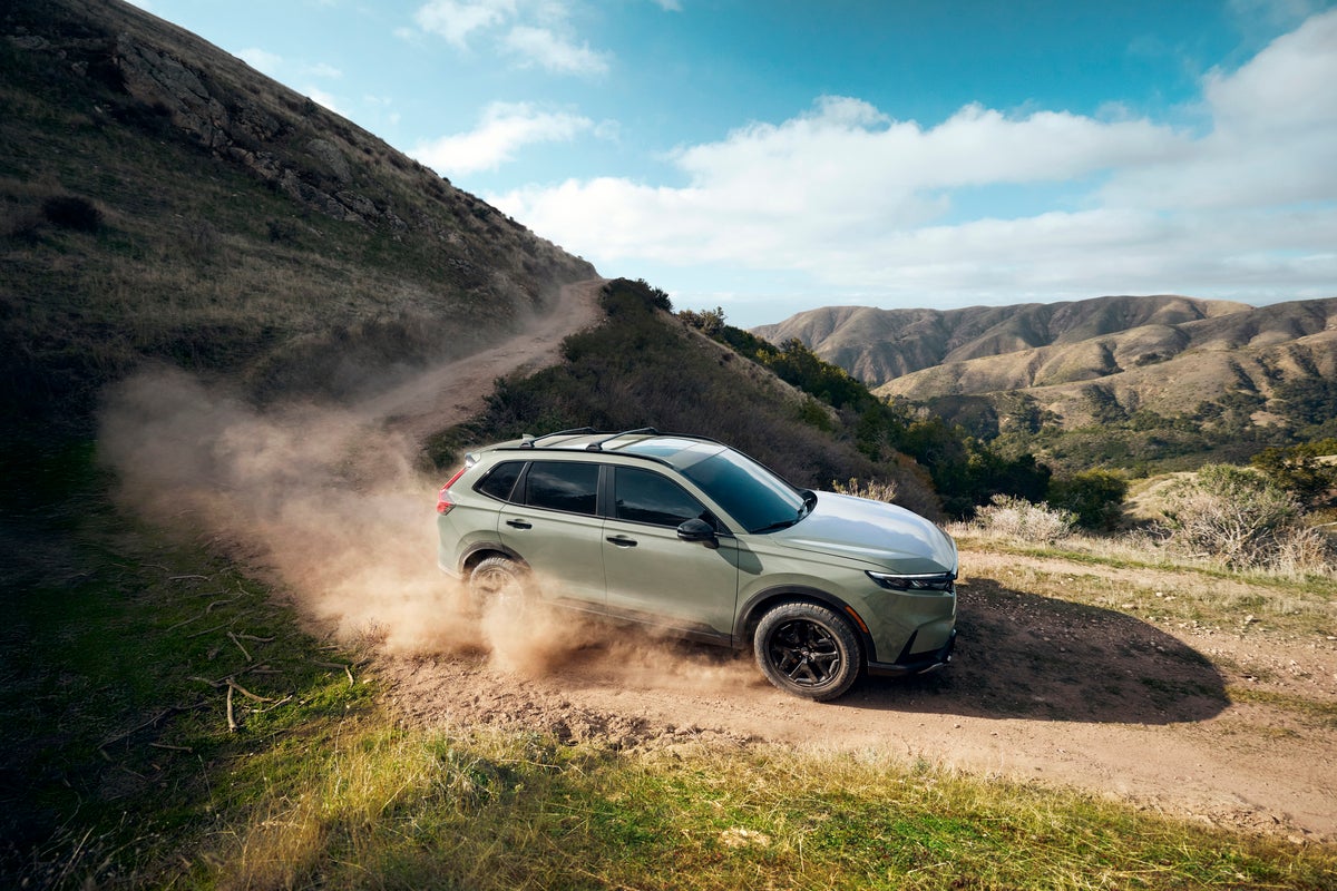 A green new Honda CRV in Phoenix drives to the right down a steep mountain dirt road.