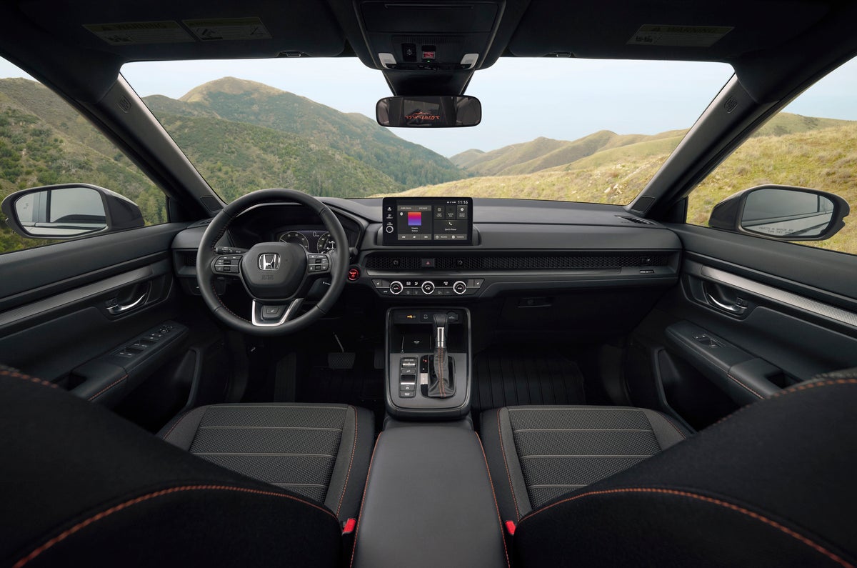 The black interior of a used Honda CRV in Phoenix is seen from the back middle seat looking forwards.